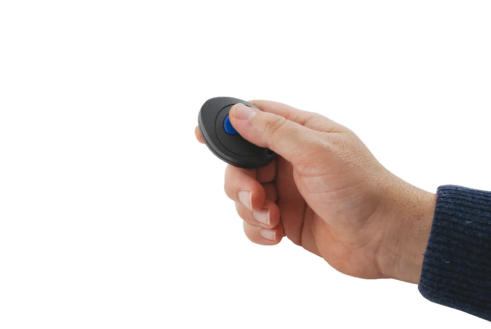 A hand pressing the button on a small portable transmitter to send a help request
