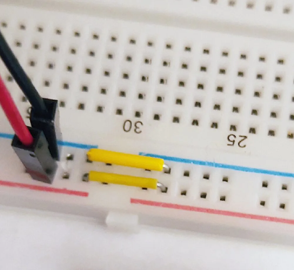 Close-up of the breadboard power rails with jumper wires bridging the gap